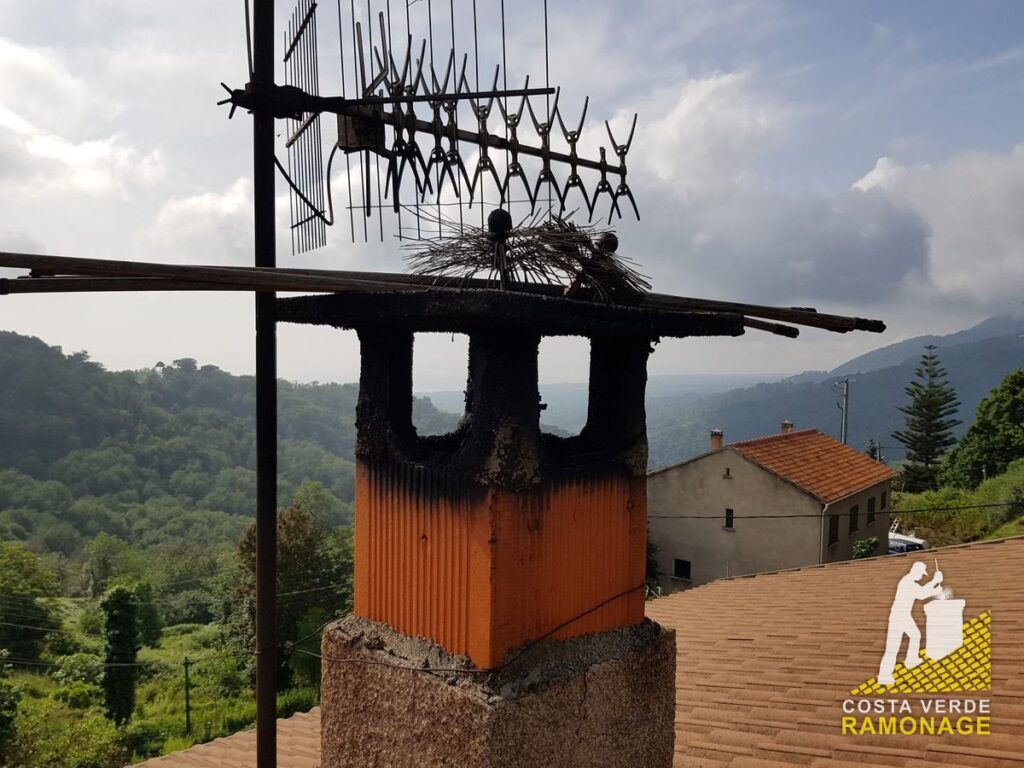 Antenne râteau montée sur une souche de cheminée, maisons et collines derrière