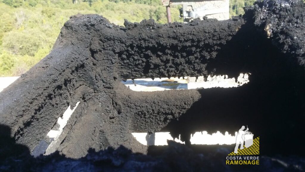 Chapeau de cheminée en béton entièrement recouvert de dépôts de suie, avant nettoyage