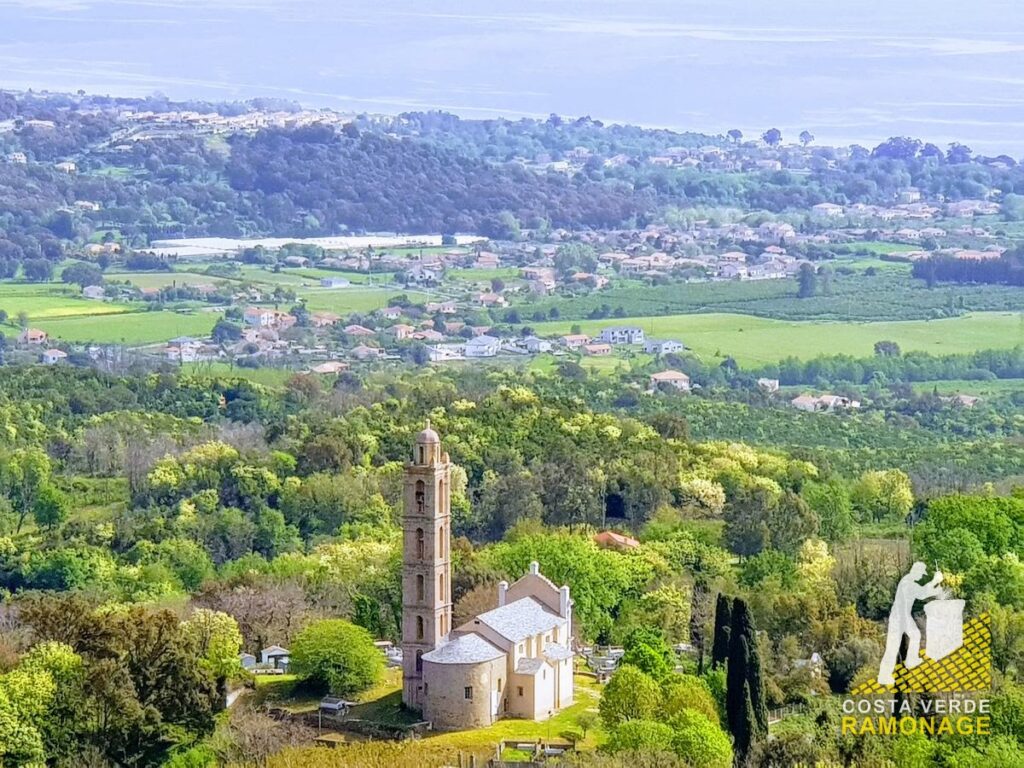 Église et son clocher au milieu des cultures de la plaine orientale, la mer à l'horizon