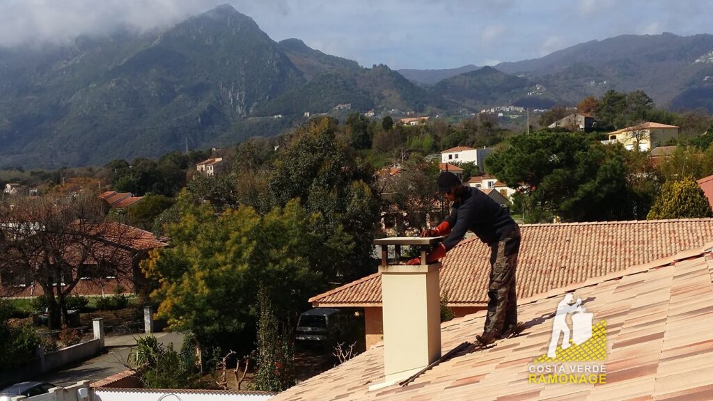 Ramoneur penché sur une souche de cheminée pour inspecter le conduit, montagnes en arrière-plan