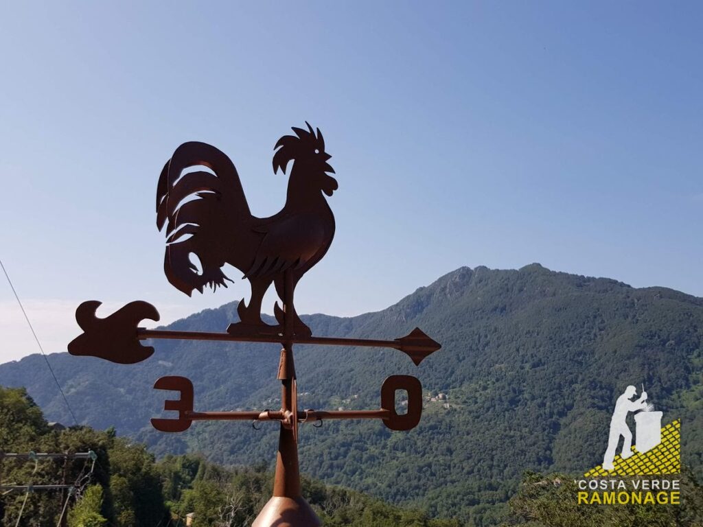 Girouette en fer forgé en forme de coq sur une souche, montagnes corses en arrière-plan