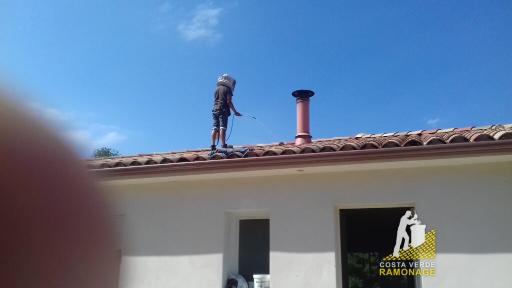 Technicien debout sur la toiture d'une maison, cannes de ramonage à la main