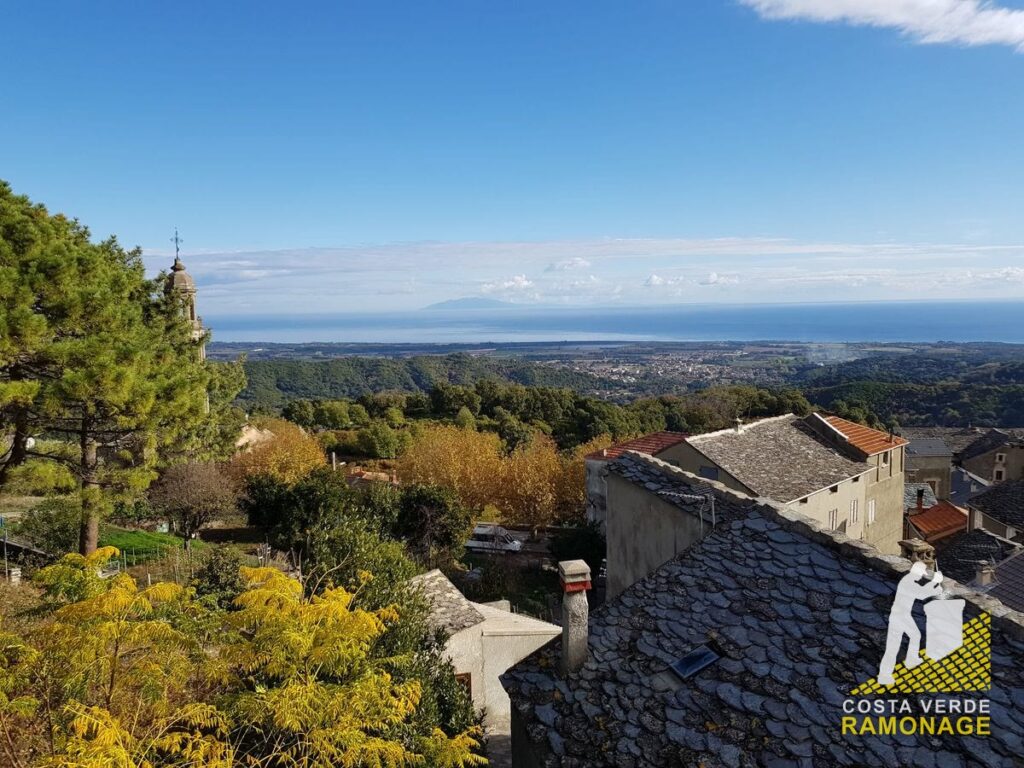 Toits de lauzes d'un village de hauteur, la plaine et la côte orientale au loin