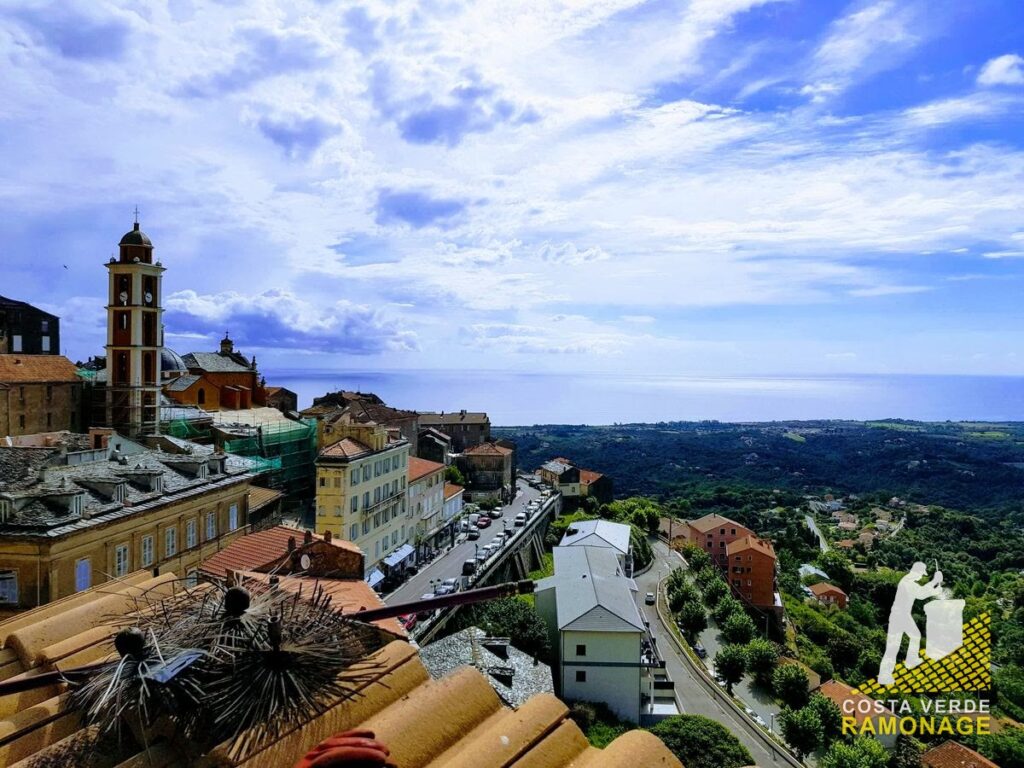 Clocher baroque et toits d'un village de hauteur, la côte orientale et la mer derrière