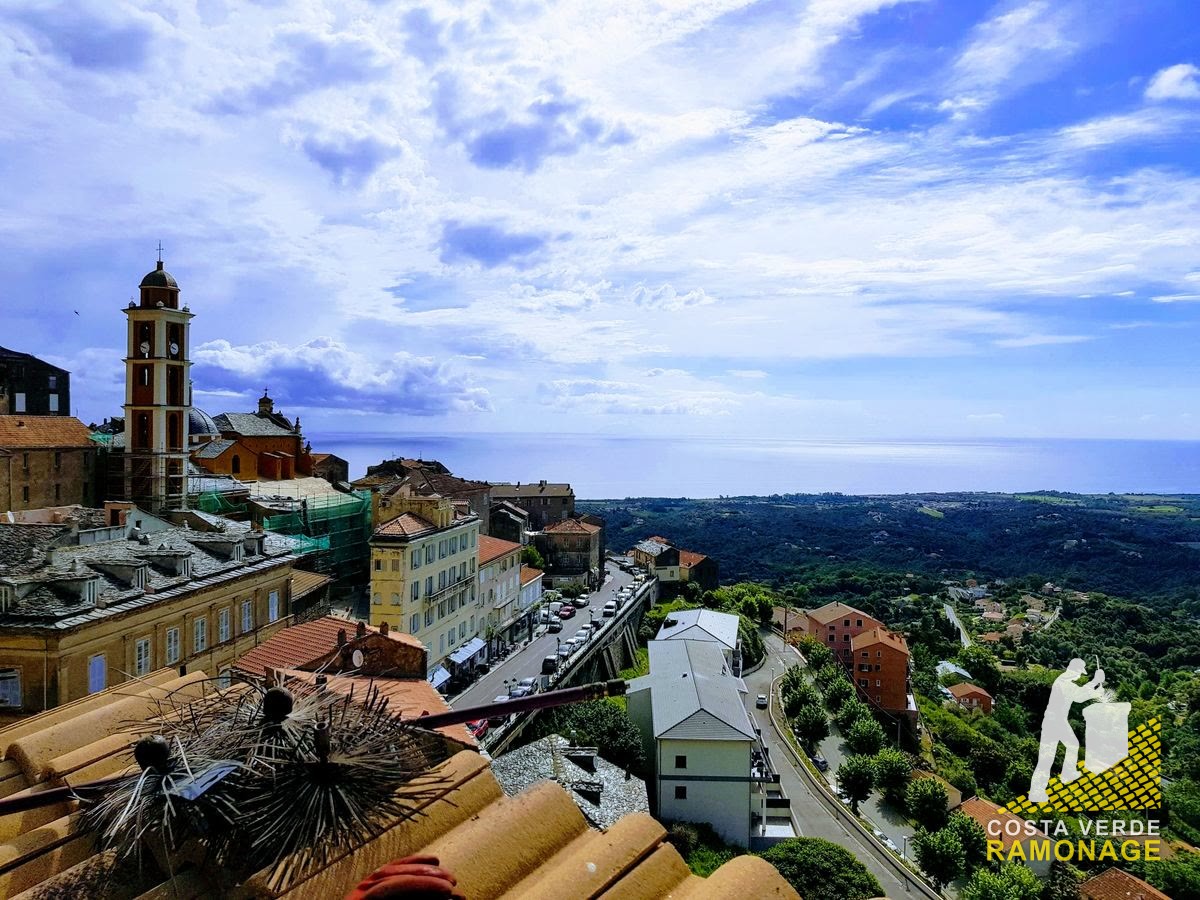 Clocher baroque et toits d'un village de hauteur, la côte orientale et la mer derrière