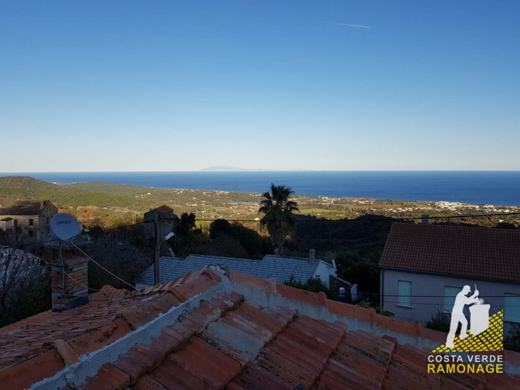 Toit de tuiles au premier plan, palmier, maisons et mer Tyrrhénienne au fond