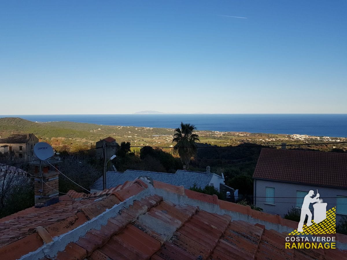 Toit de tuiles au premier plan, palmier, maisons et mer Tyrrhénienne au fond